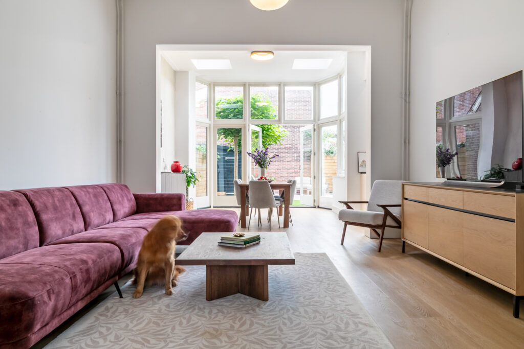 Modern living room with large windows and pink sofa.