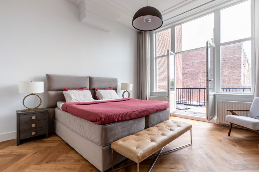 Modern bedroom with balcony and large windows.