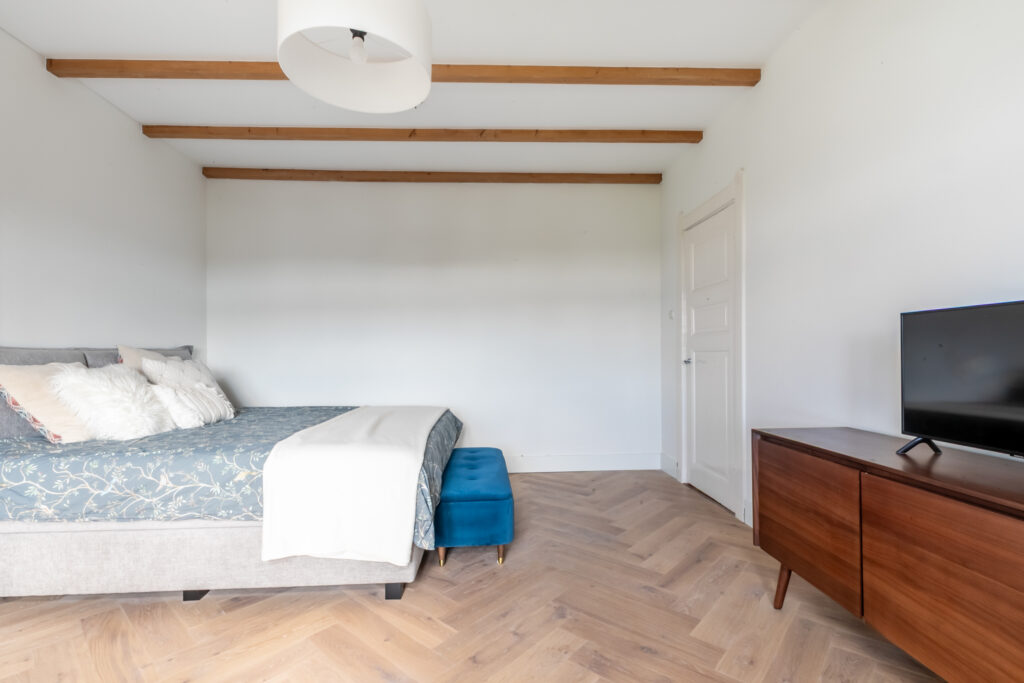 Modern bedroom with bed, TV, and wooden floor.