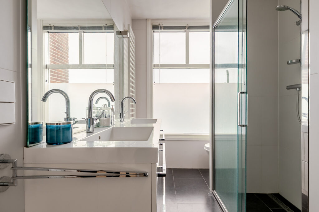 Modern bathroom with glass shower and dual sinks.