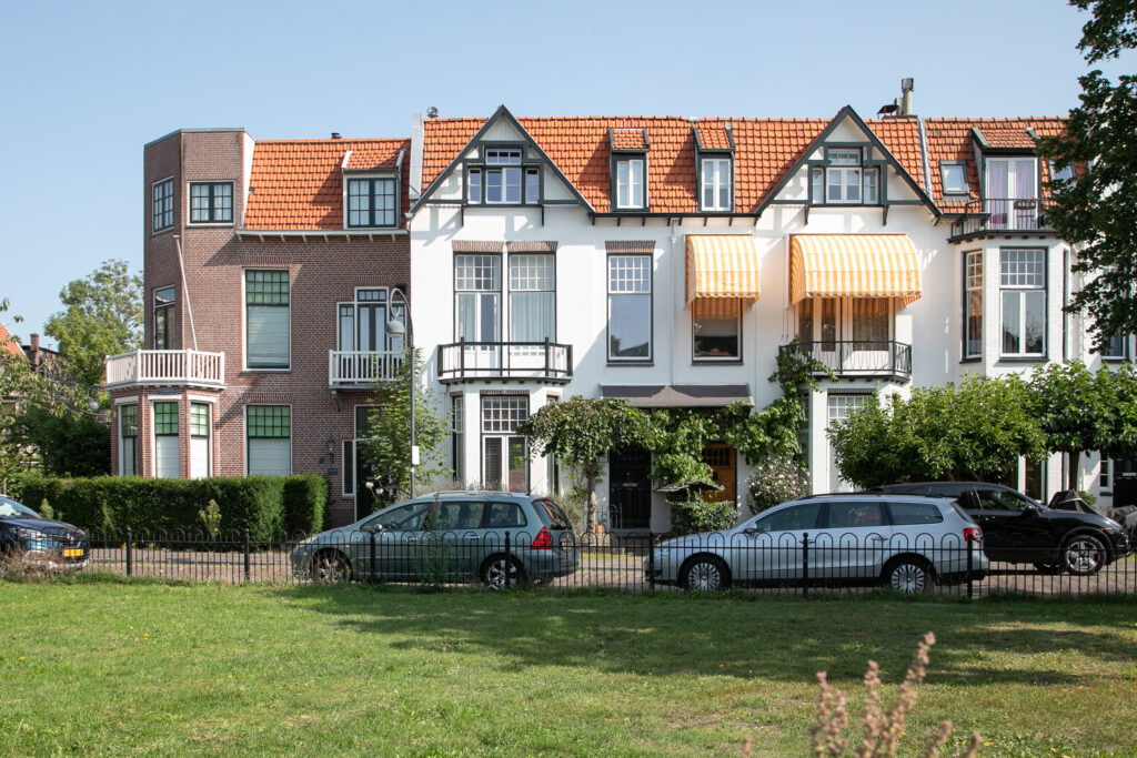 Row of houses with orange awnings and parked cars.