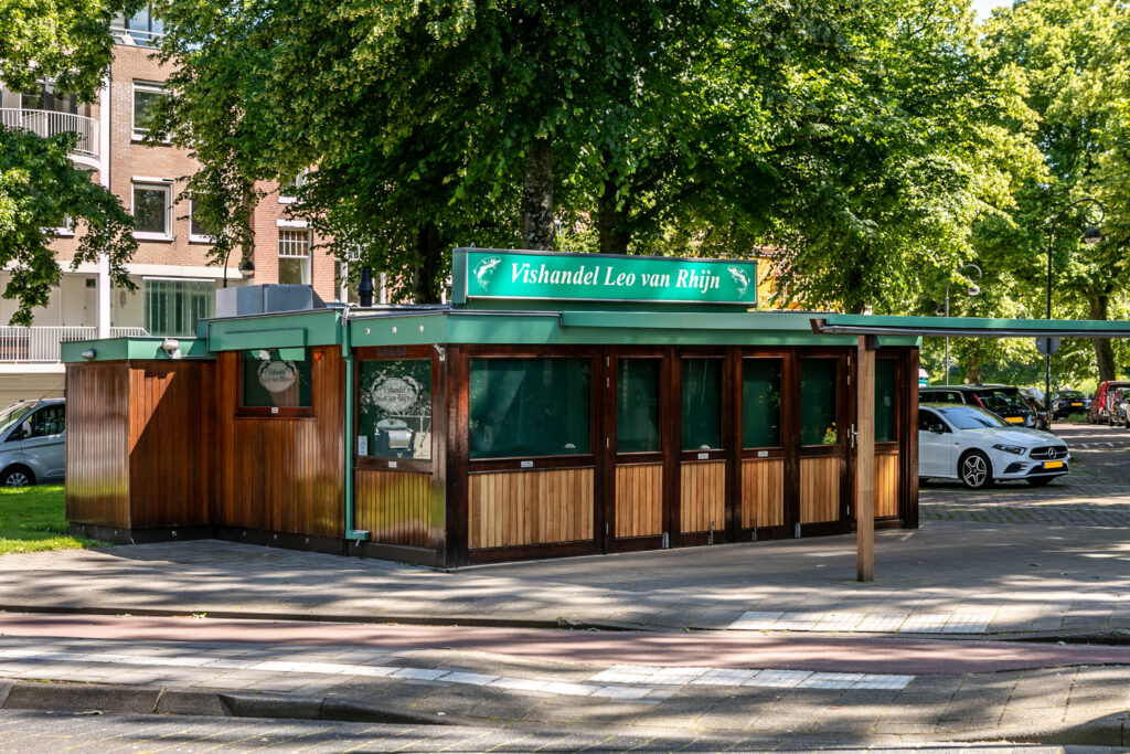 Outdoor fish shop surrounded by trees and cars.