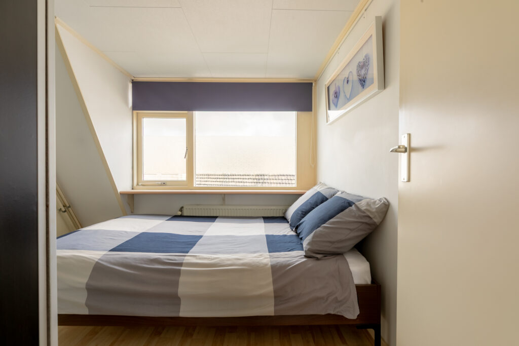 Cozy bedroom with window and striped bedding.