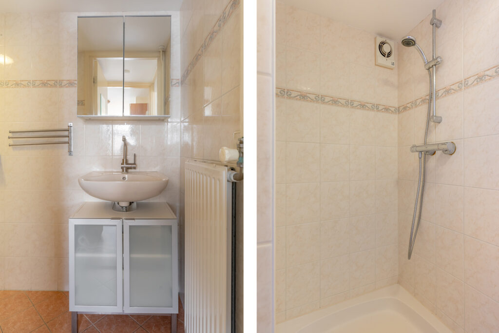 Bathroom sink and tiled shower stall view.