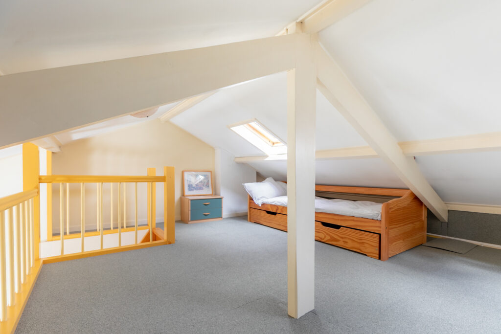 Cozy attic bedroom with single bed and skylight.