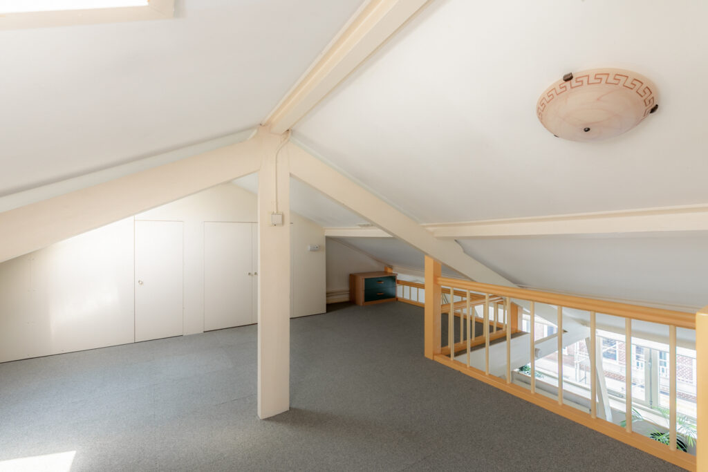 Spacious attic with white walls and carpet