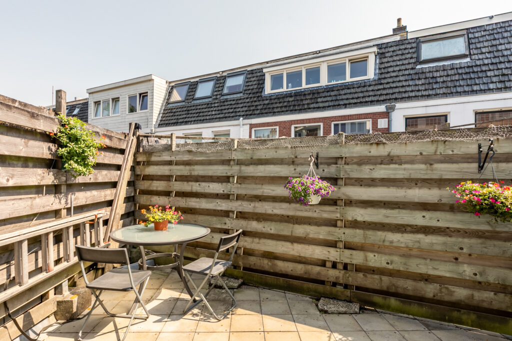 Sunny patio with chairs and flower decorations.