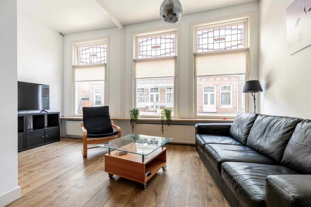 Modern living room with large windows and leather sofa.