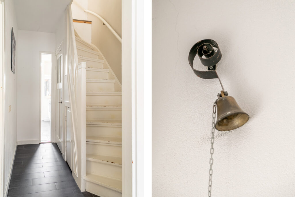 White staircase and vintage bell on white wall.