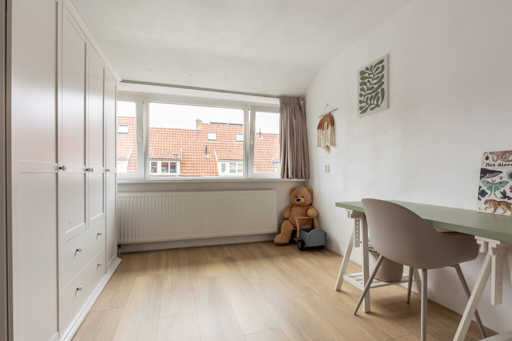 Cozy bedroom with desk and teddy bear.