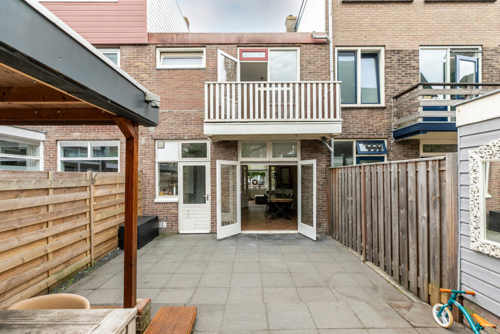 Backyard with open patio doors and balcony above.