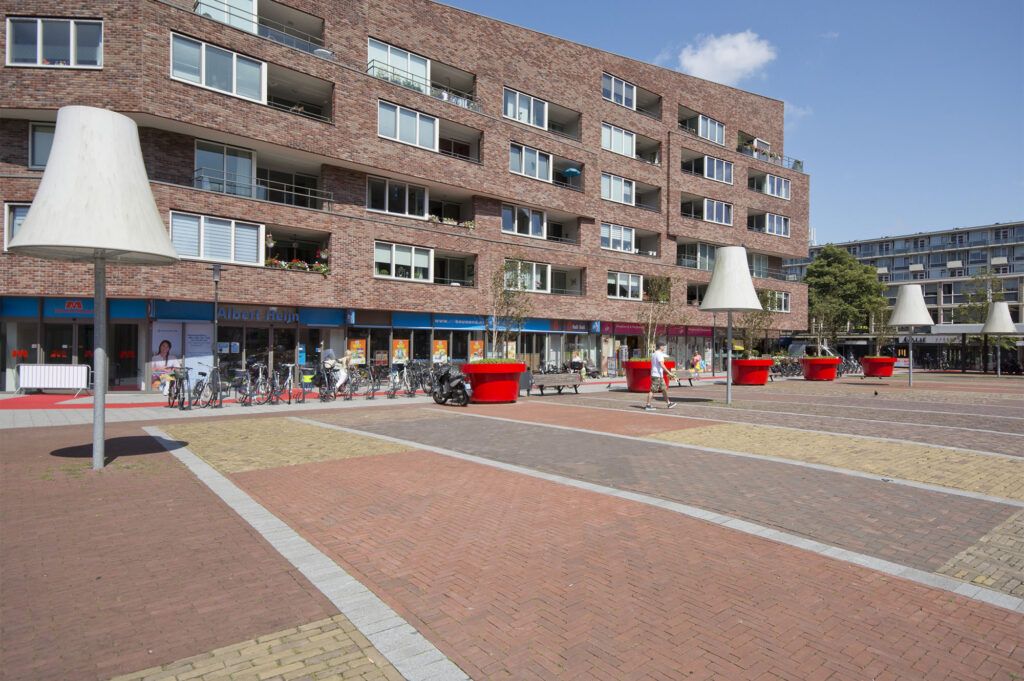 Urban plaza with brick buildings and modern sculptures.