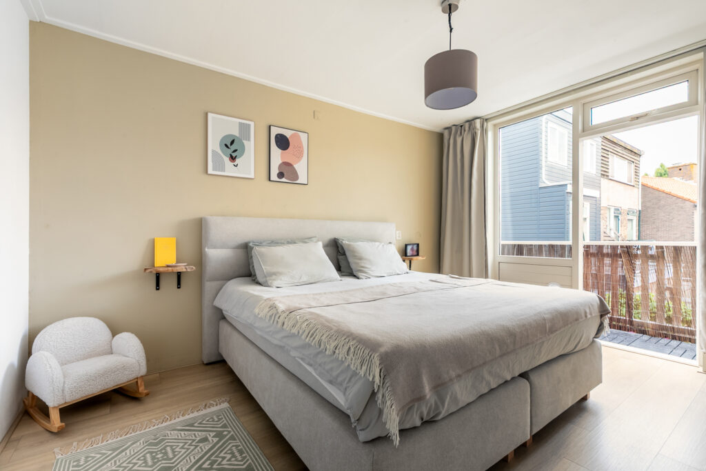 Modern bedroom with large bed, artwork, and balcony view.