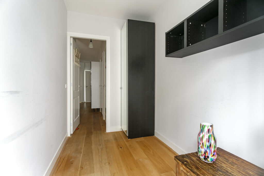 Narrow hallway with wooden floors and a vase