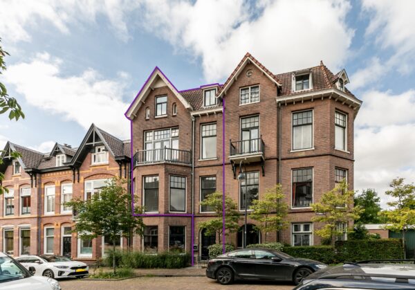Historic brick house with large windows, blue sky.