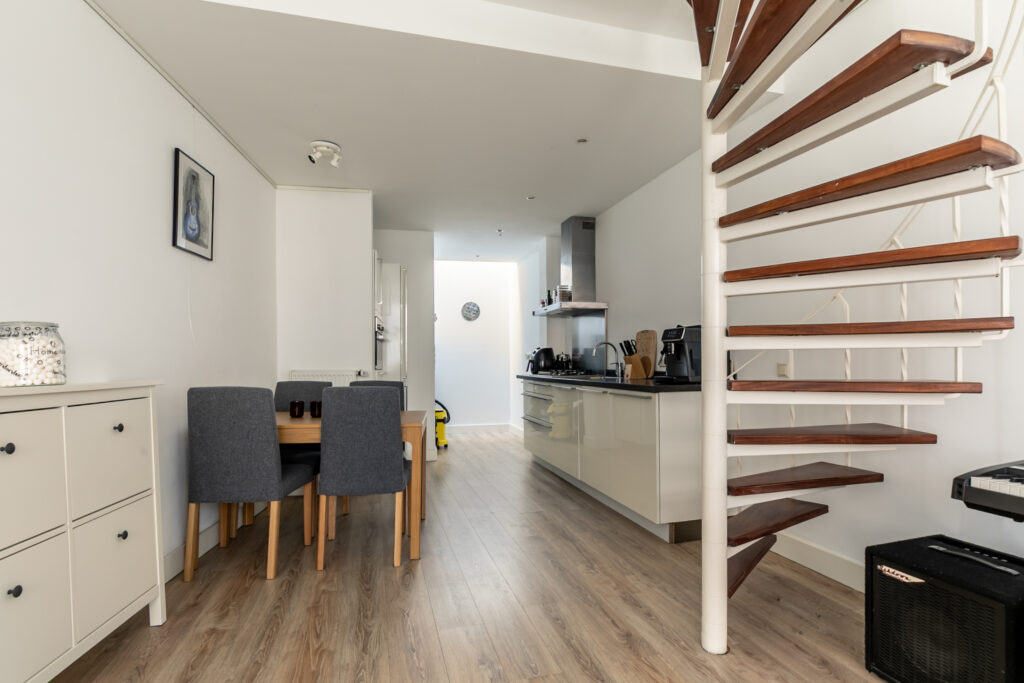 Modern kitchen and dining area with spiral staircase.