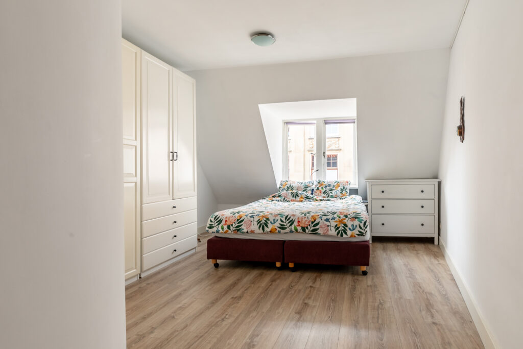 Bright bedroom with floral bedding and white furniture.
