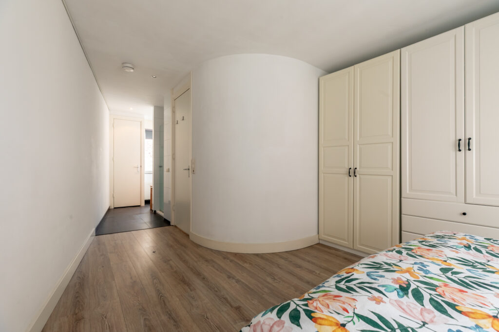 Modern bedroom with wooden floor and floral bedspread.