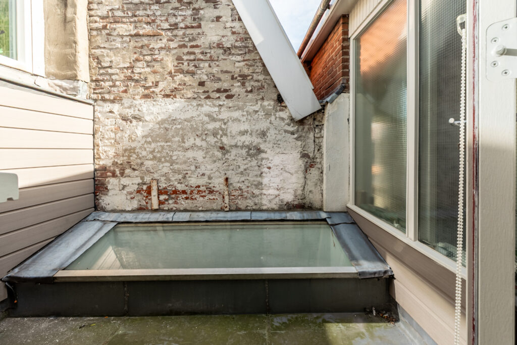 Rooftop skylight with surrounding brick walls and windows.