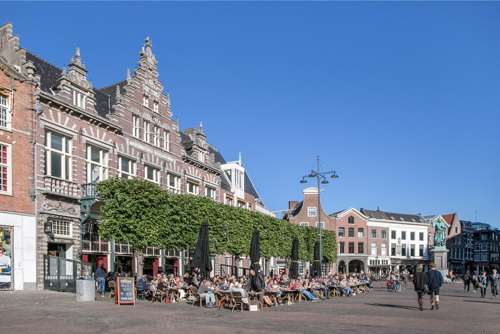 Historic city square with people and outdoor cafes.