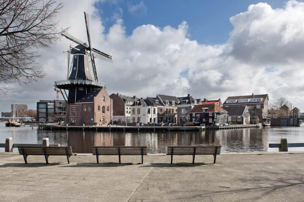 Windmill by canal with cloudy sky in Haarlem.