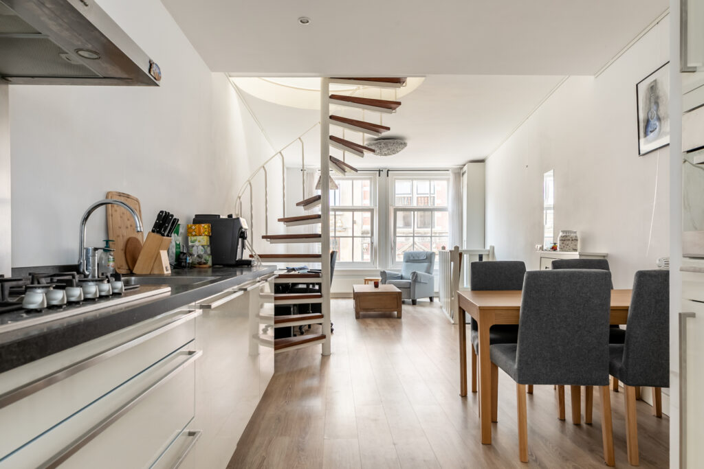 Modern open-plan kitchen and dining area with spiral staircase.