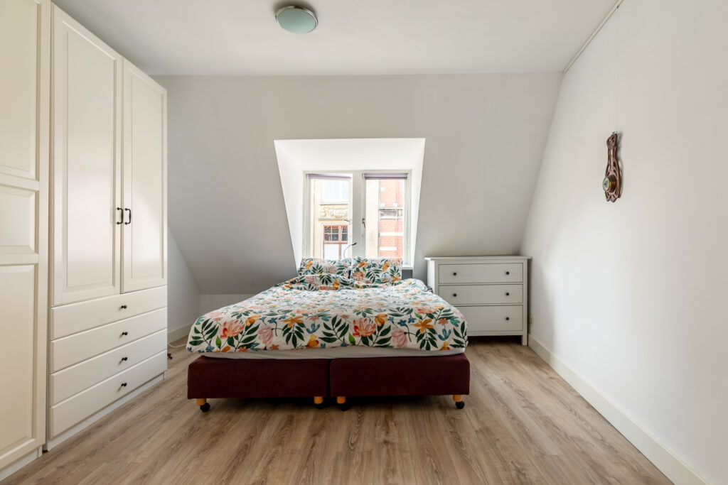Bright bedroom with floral bedding and white furniture.