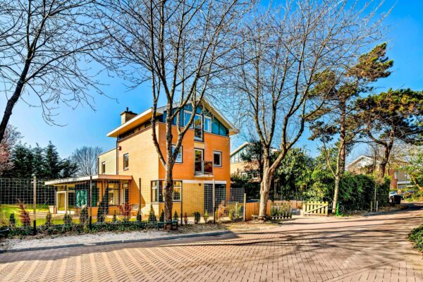 Modern brick house with trees and clear sky.