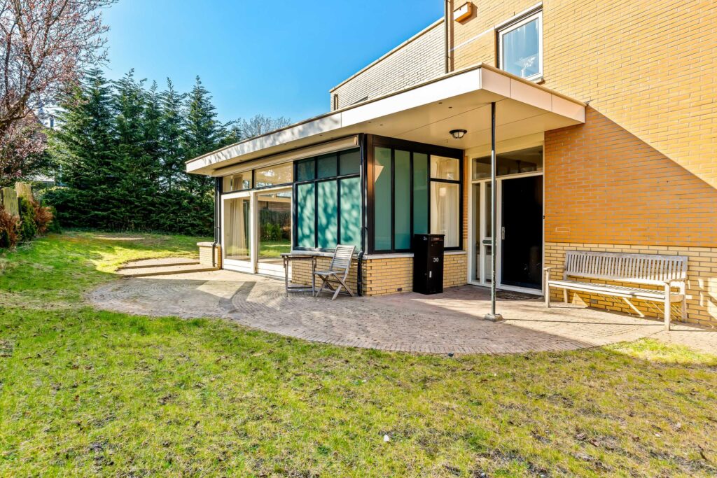 Modern house with glass windows and green yard.