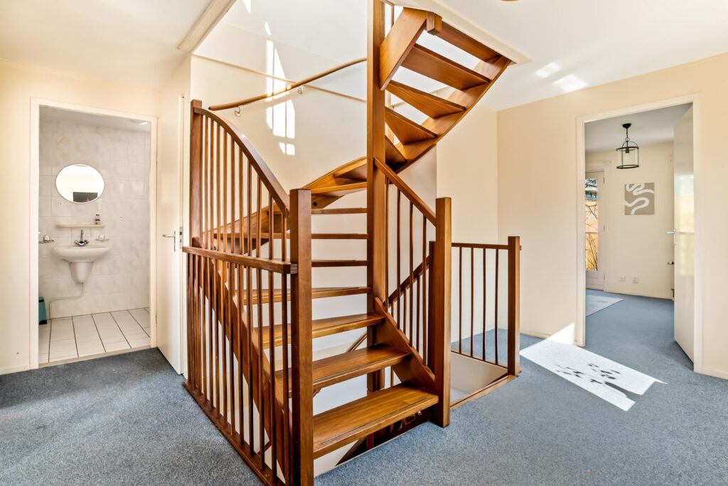 Wooden staircase with blue carpeted hallway.