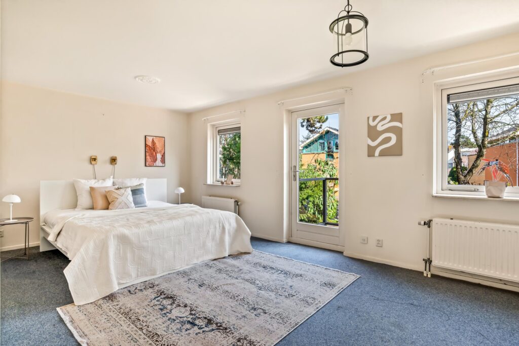 Bright airy bedroom with large windows and elegant decor.
