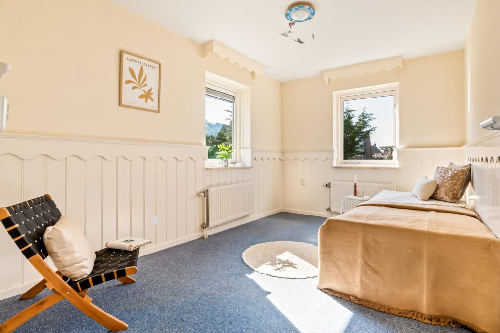 Bright bedroom with chair, bed, and wall art.
