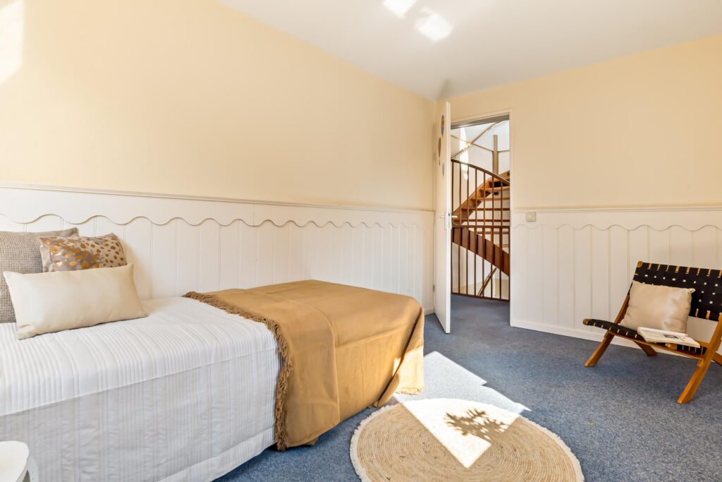 Cozy bedroom with bed, chair, and open door.