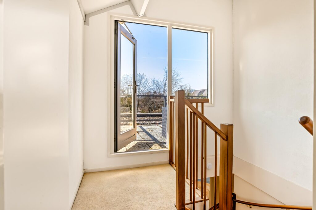 Bright staircase with glass door opening to outside view.