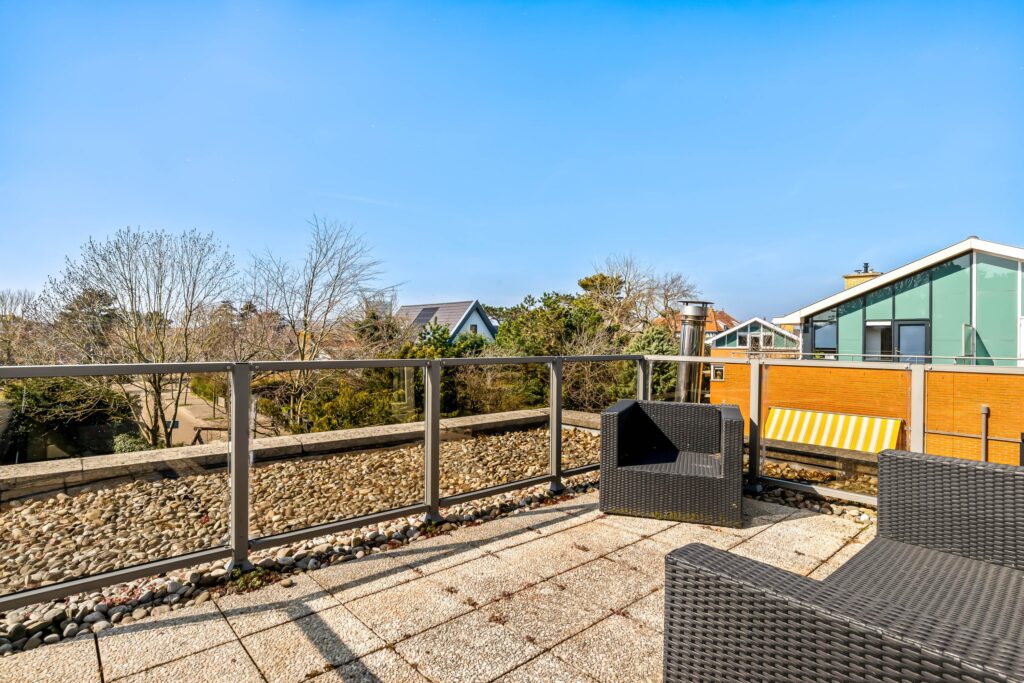 Sunny patio with chairs and scenic view.