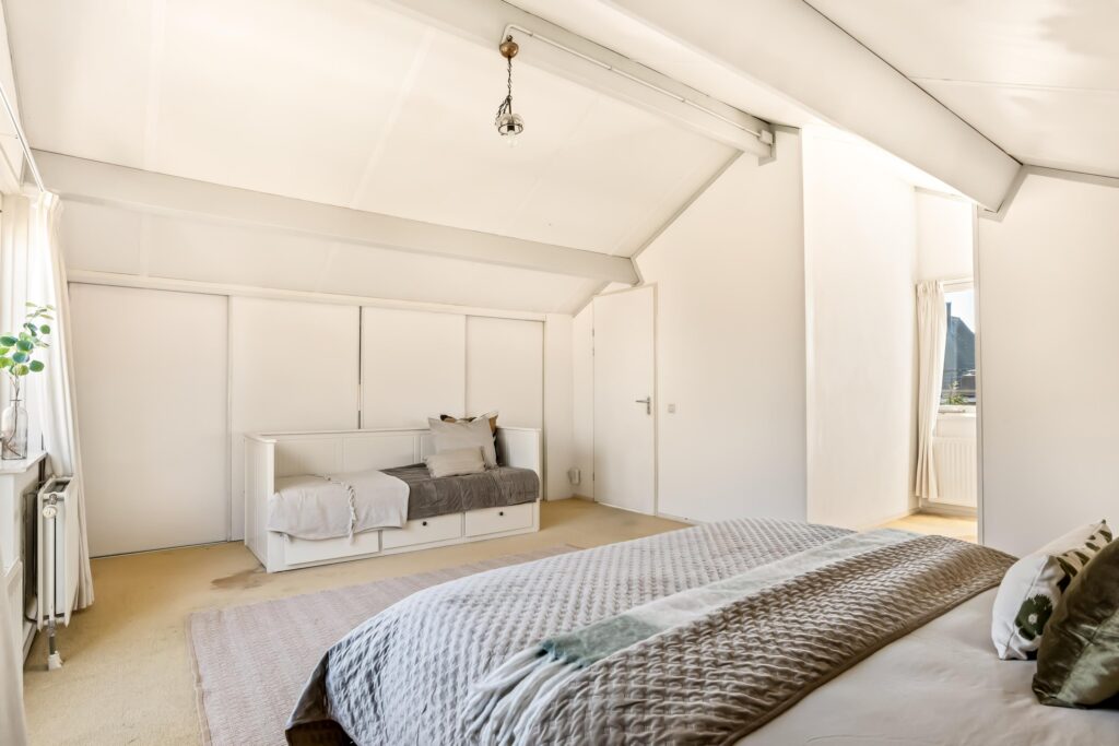 Spacious bedroom with cozy bed and daylight.