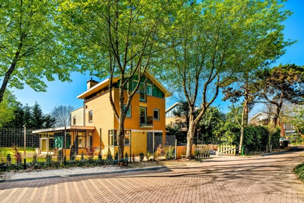 Yellow house surrounded by trees on sunny day.