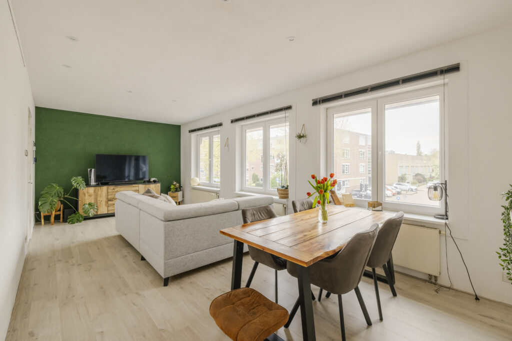 Modern living room with green accent wall and windows.