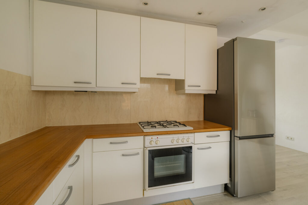 Modern kitchen with white cabinets and stainless fridge.