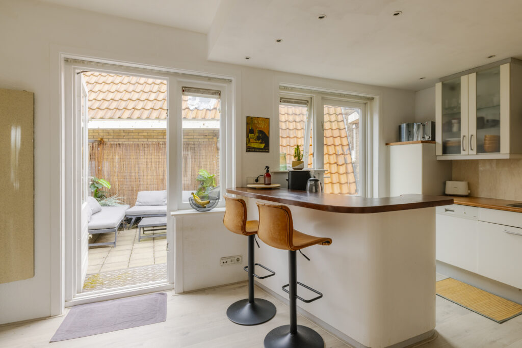 Modern kitchen with bar stools and patio view.