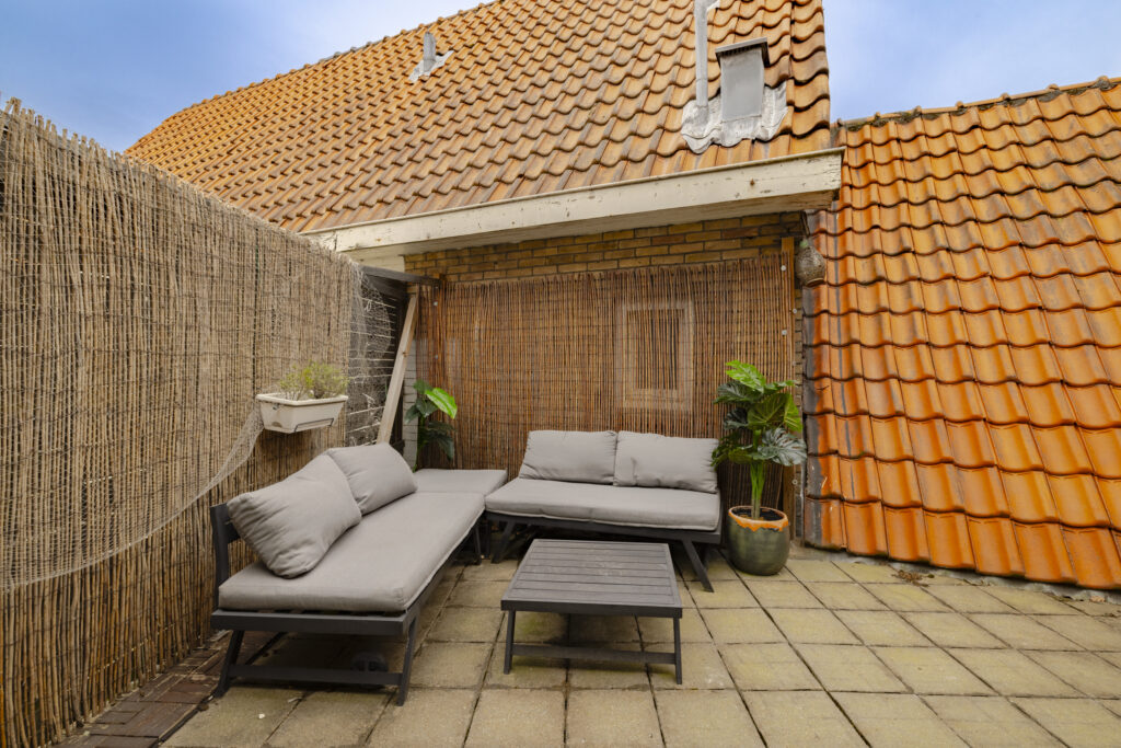 Cozy rooftop patio with sofas and bamboo decor.