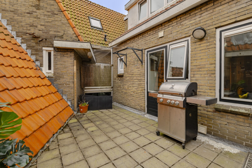 Outdoor patio with barbecue grill and tiled roof.