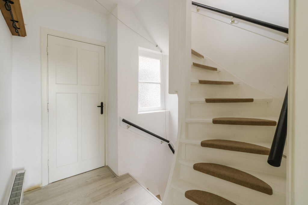 White staircase with carpeted steps and white door.