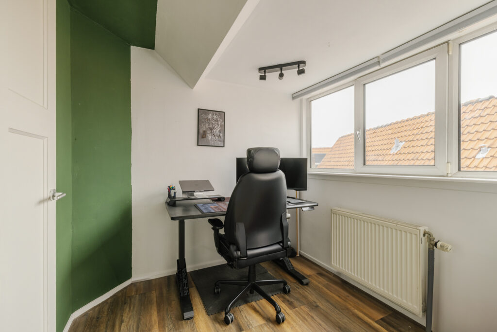 Modern home office with computer and ergonomic chair.