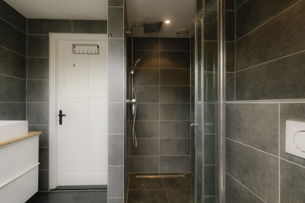 Modern bathroom with glass shower and tiled walls.