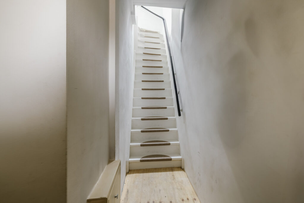Narrow staircase with white walls and handrail.