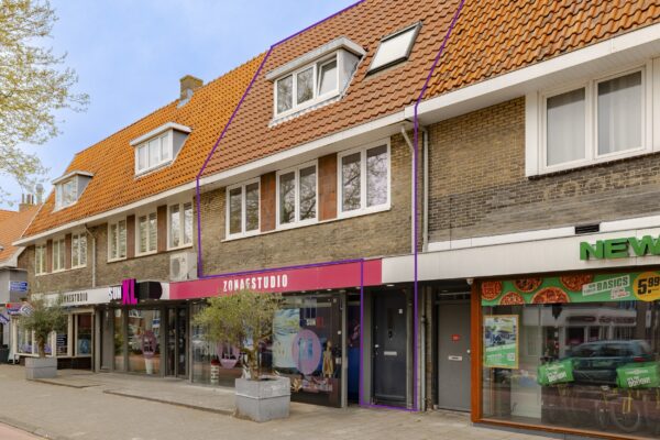 Street view of shops and apartments with orange roof.