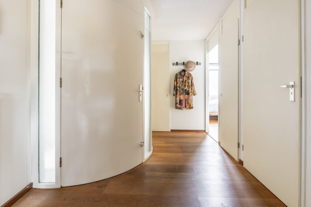 Bright hallway with wooden floor and hanging coat.
