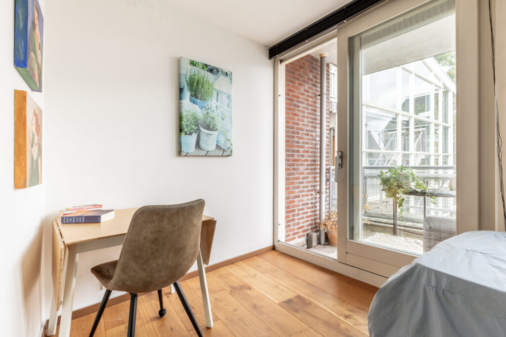 Cozy room with desk, chair, and balcony view.