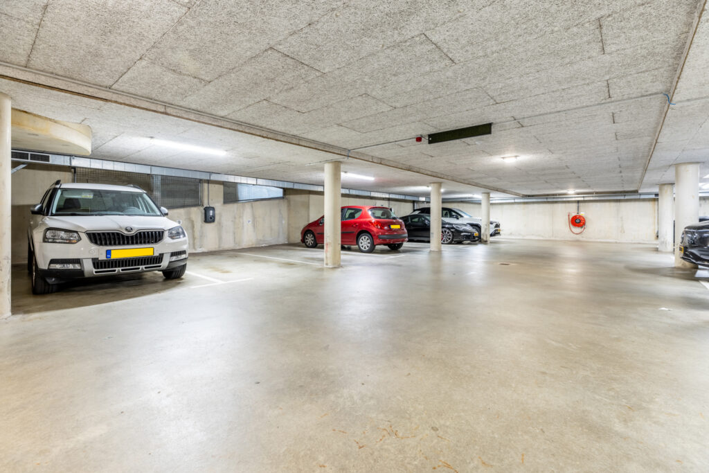 Spacious underground parking garage with multiple cars parked.